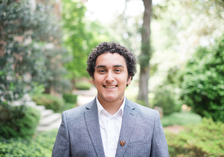 Nuren Lara, dressed in a gray suit jacket and white button-down shirt, standing on the Mercer campus.