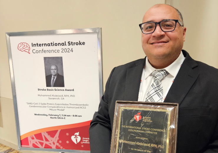 Dr. Abdelsaid standing holding plaque.