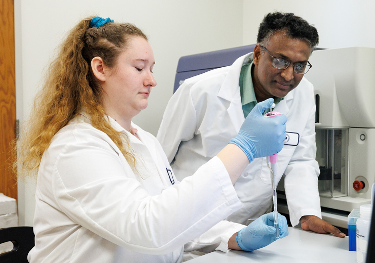 Two scientists in lab coats work together in a laboratory.